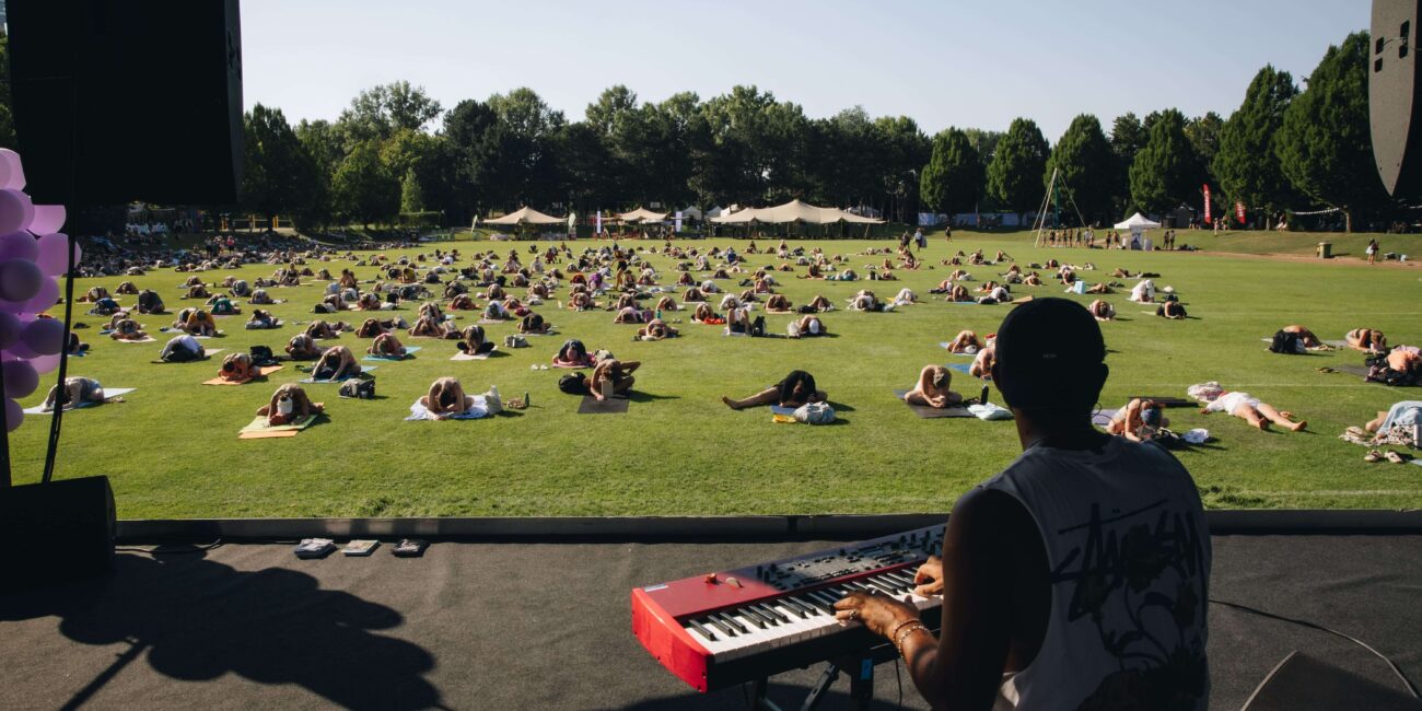 Musiker spielt Keyboard, während die große Gruppe entspannt auf der Wiese liegt